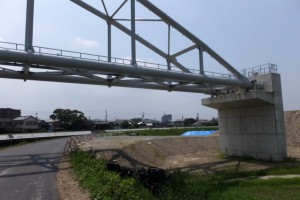 舗装工事を終えて開放された勢田川の左岸堤防道路から望む水管橋の橋台